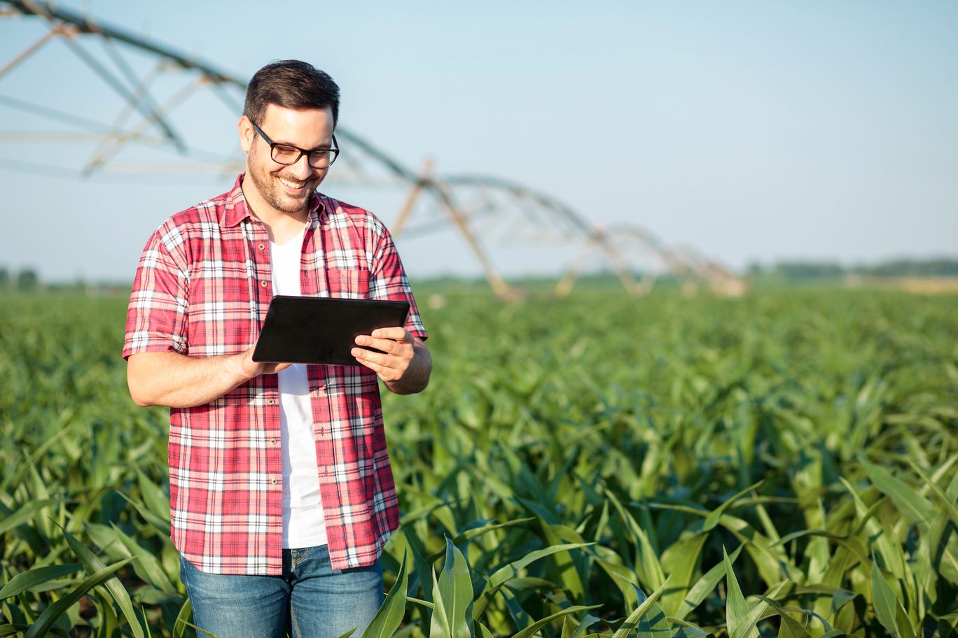 Farmer holding a tablet in a field with a center pivot irrigation system
